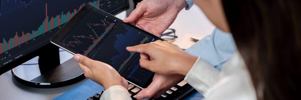 Group of traders discussing on office desk, monitoring stock market on monitor at office workplace. Businessman and broker analyzing stock graph together at stock trading company. Trailblazing