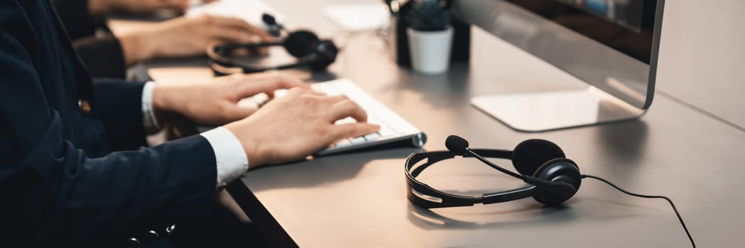 Panorama focus headset on call center workspace desk with blur background of operator team or telesales representative engage in providing client with customer support service or making sales. Prodigy