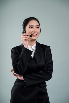 Attractive asian female call center operator with happy smile face advertises job opportunity on empty space, wearing a formal suit and headset on customizable isolated background. Enthusiastic