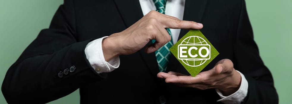 Eco-friendly corporate promoting sustainable and green business concept with businessman hold ECO symbol paper as environmental protection commitment using clean energy with zero CO2 emission. Alter