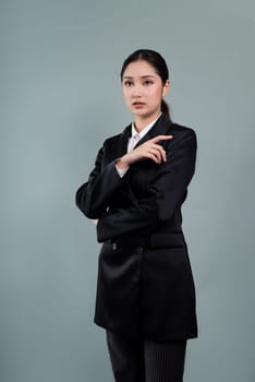 Confident young businesswoman stands on isolated background, posing in formal black suit. Office lady or manager with smart and professional appearance. Enthusiastic