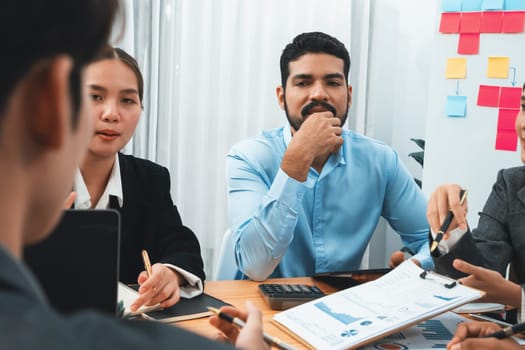 Multiracial analyst team use BI dashboard data to analyze financial report on meeting table. Group of diverse business people utilize data analysis by FIntech for business marketing decision. Concord