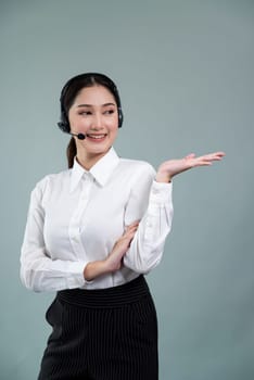 Asian female call center operator with smile face advertises job opportunity, wearing a formal suit and headset holding hand gesture for product on customizable isolated background. Enthusiastic