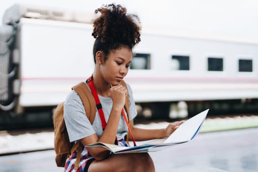 Asian teenage girl african american traveler dressed in casual wear holding map and searching right direction of route