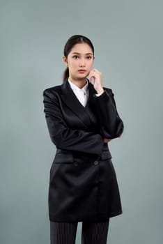 Confident young businesswoman stands on isolated background, posing in formal black suit. Office lady or manager with smart and professional appearance. Enthusiastic