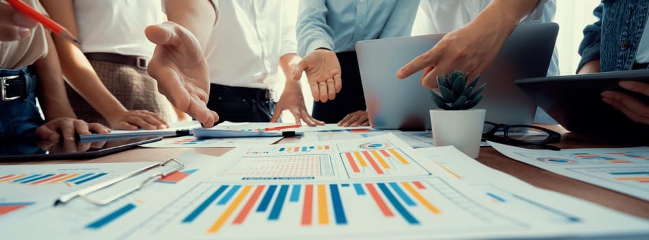 Focus panorama shot of chart and graph paper with blur analyst team utilize BI Fintech to analyze financial dashboard, brainstorm and analyzing report paper on table for business insight. Scrutinize