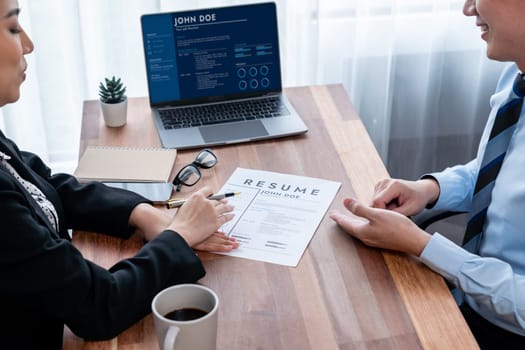 Conversational job interview between interviewer and candidate. Asian female job applicant present her performance and qualification by digital resume on laptop and CV paper to HR manager. Jubilant