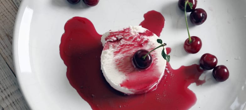 Food background.Ice cream with cherries on a white plate, poured with red jam.Top view