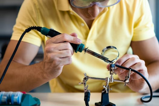 Close up of teen boy in electronics class working on a project alone. Education concept.