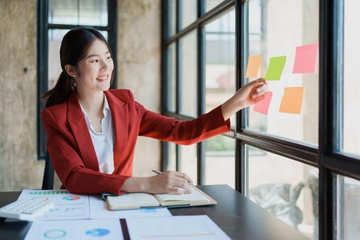 Beautiful young teen asian businesswoman using note pad thinking with planning working on financial document, tax, exchange, accounting and Financial advisor.