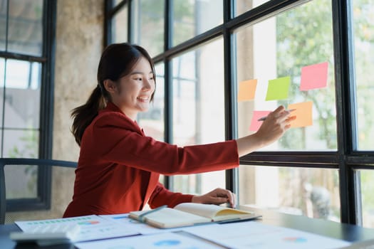 Beautiful young teen asian businesswoman using note pad thinking with planning working on financial document, tax, exchange, accounting and Financial advisor.