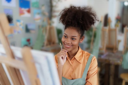 Beautiful american african artist woman painting in art studio at the university classroom.