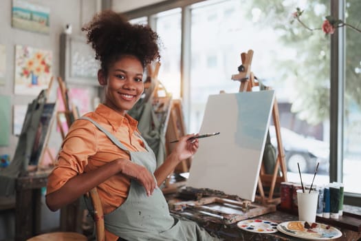 Beautiful american african artist woman painting in art studio at the university classroom.