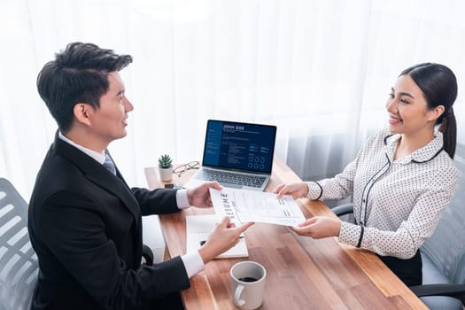 Conversational job interview between interviewer and candidate. Asian female job applicant present her performance and qualification by digital resume on laptop and CV paper to HR manager. Jubilant