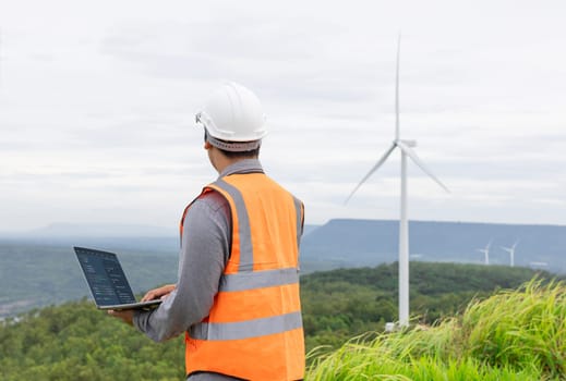 Engineer working on a wind farm atop a hill or mountain in the rural. Progressive ideal for the future production of renewable, sustainable energy. Energy generation from wind turbine.