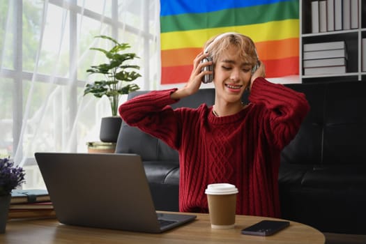 Carefree teenage gay man enjoying favorite track, listening to music on headphones. LGBTQ people lifestyle concept.