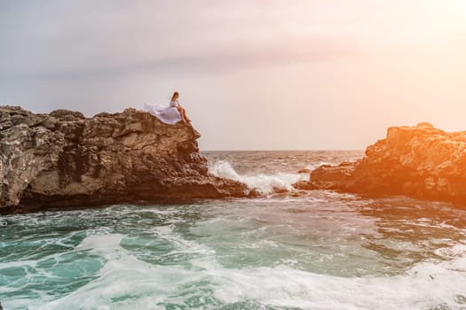 Woman sea white dress. A woman in a storm sits on a stone in the sea. Dressed in a white long dress, waves crash against the rocks and white spray rises