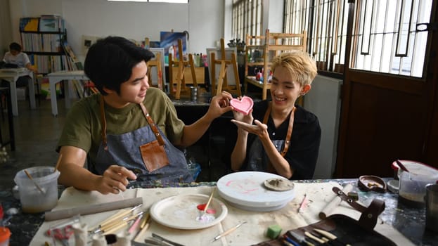 Happy asian gay couple enjoying creative process, creating handmade ceramics in art class. LGBTQ, indoors lifestyle activity concept.