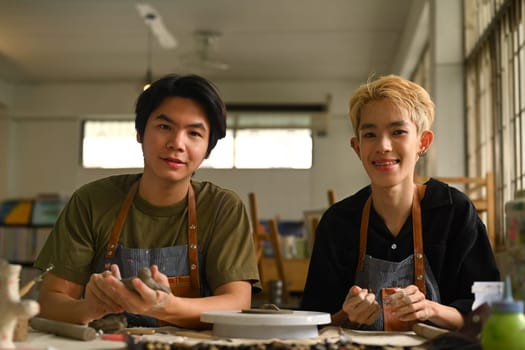 Image of ceramics art teacher and student sitting in pottery workshop. Indoors lifestyle activity, handicraft, hobbies concept.