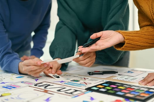 Group of application designers testing and discussing on new app features, collaborating on new project in office. UX UI design concept.