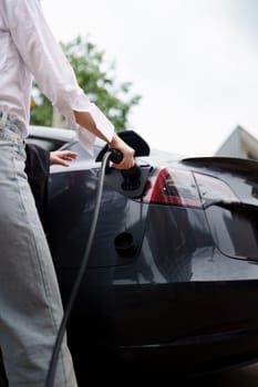 Electric car charging, Woman connecting a charging cable to a car. Green Energy concept.