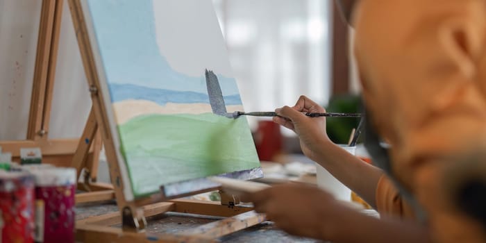 Close up of african american male painter at work painting on canvas in art studio. creation and inspiration at an artists painting studio.