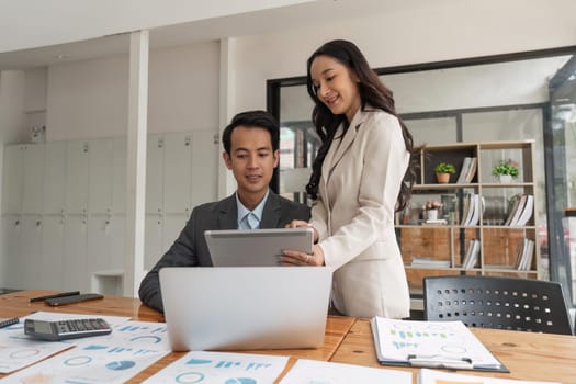 Happy businesspeople working together in the office while using laptop analyze the company finances and tax.