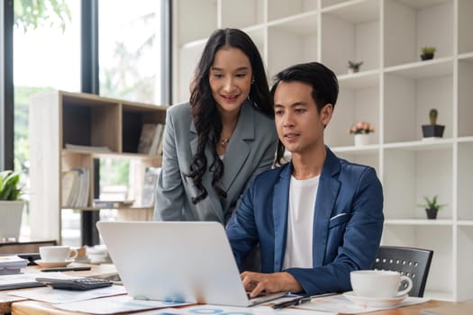 Happy businesspeople working together in the office while using laptop analyze the company finances and tax.