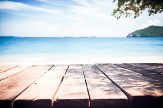 Top of wood table with seascape, blur calm sea and sky at tropical beach background. Empty table ready for your product display montage. Summer vacation background concept.