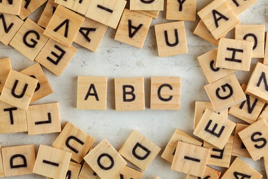 Top down view, pile of square wooden blocks with letters ABC on white board. 