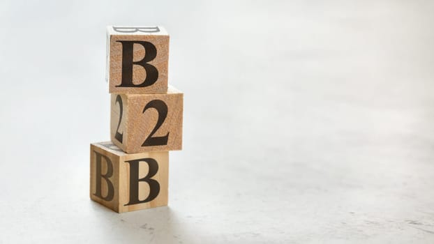 Pile with three wooden cubes - letters B2B meaning Business to Business on them, space for more text / images at right side.