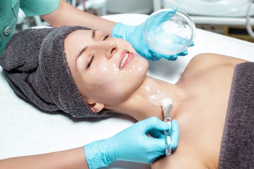 beautician applies face mask with a brush to the beautiful young woman in Spa salon. cosmetic procedure skin care. Microdermabrasion
