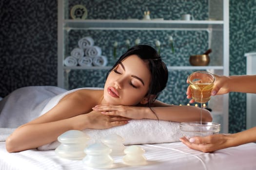 Relaxed beautiful young woman in spa salon. Beauty treatments with oil