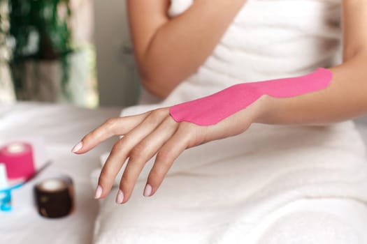 Young woman wearing pink kinesio therapy tape on her hand