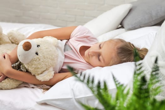 Cute little child girl sleeping with teddy bear in her bed