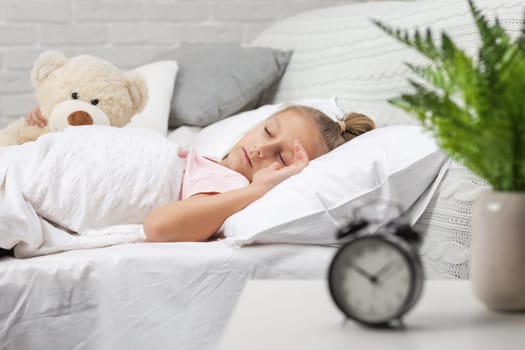 Cute little child girl sleeping with teddy bear in her bed