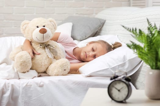 Cute little child girl sleeping with teddy bear in her bed