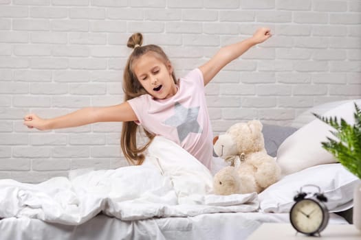 cute little child girl wakes up from sleep in bed in the morning
