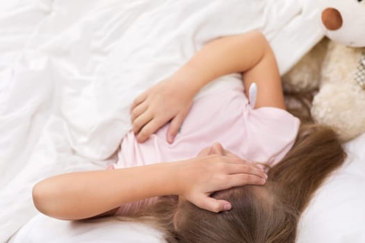 Sick little child girl lying in bed with thermometer. Cold flu season