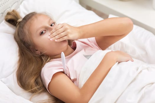 Sick little child girl lying in bed with thermometer. Cold flu season
