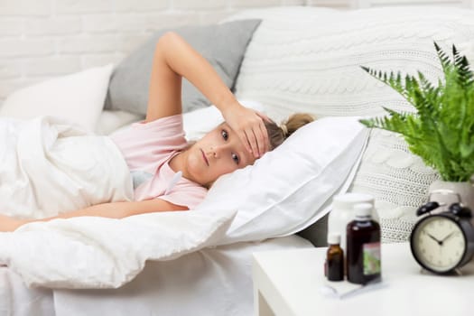 Sick little child girl lying in bed with thermometer. Cold flu season