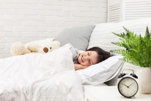 Cute little child girl sleeping with teddy bear in her bed