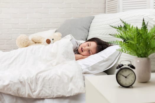 Cute little child girl sleeping with teddy bear in her bed