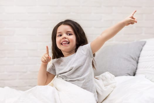 cute happy smiling little child girl wakes up from sleep in bed in the morning