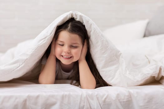 happy morning baby in bed. child dabbles in bed. child covers his ears