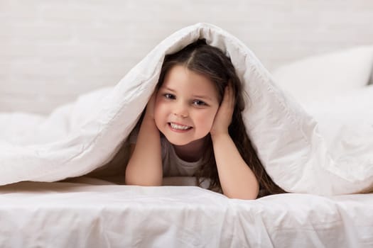 happy morning baby in bed. child dabbles in bed. child covers his ears