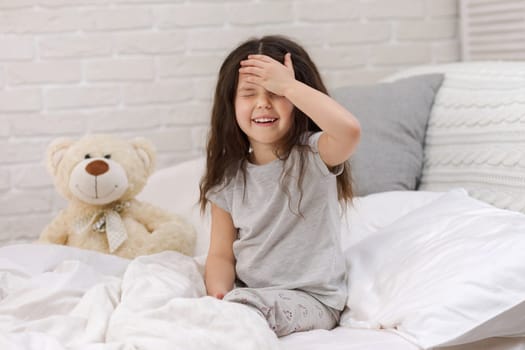 cute little child girl wakes up from sleep in bed in the morning