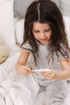 Sick little child girl lying in bed with thermometer. Cold flu season