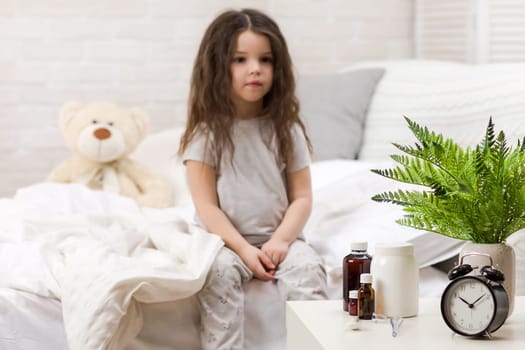 Sick little child girl lying in bed with thermometer. Cold flu season