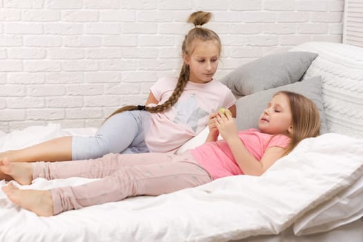 two cute children girls playing in the bedroom. pajama party and friendship.
